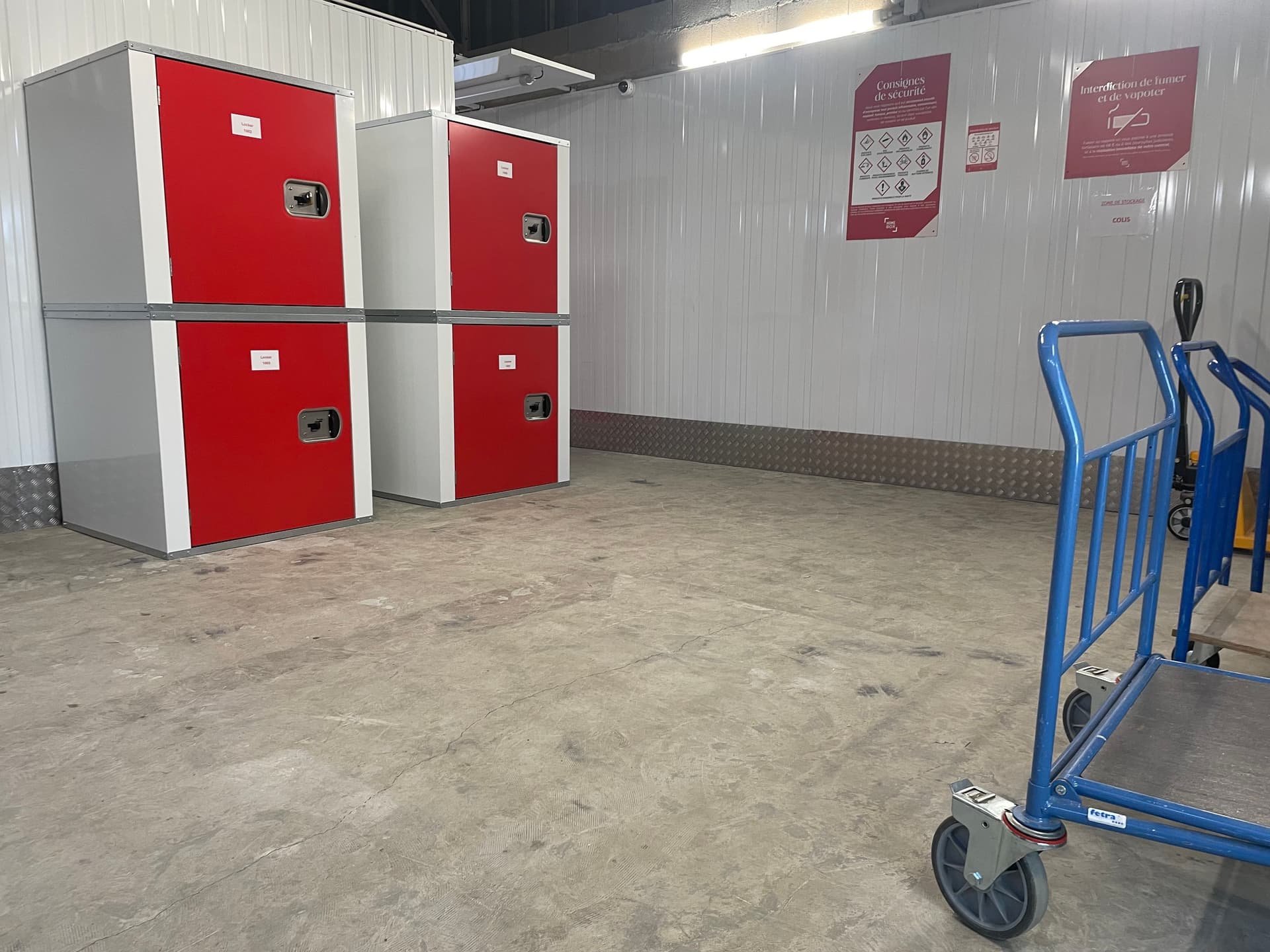 Casiers de consigne rouges et chariot de manutention dans une zone de stockage du centre HOMEBOX Lisieux