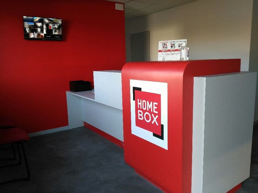 Comptoir d'accueil rouge et blanc avec écran de vidéosurveillance du centre HOMEBOX Vichy