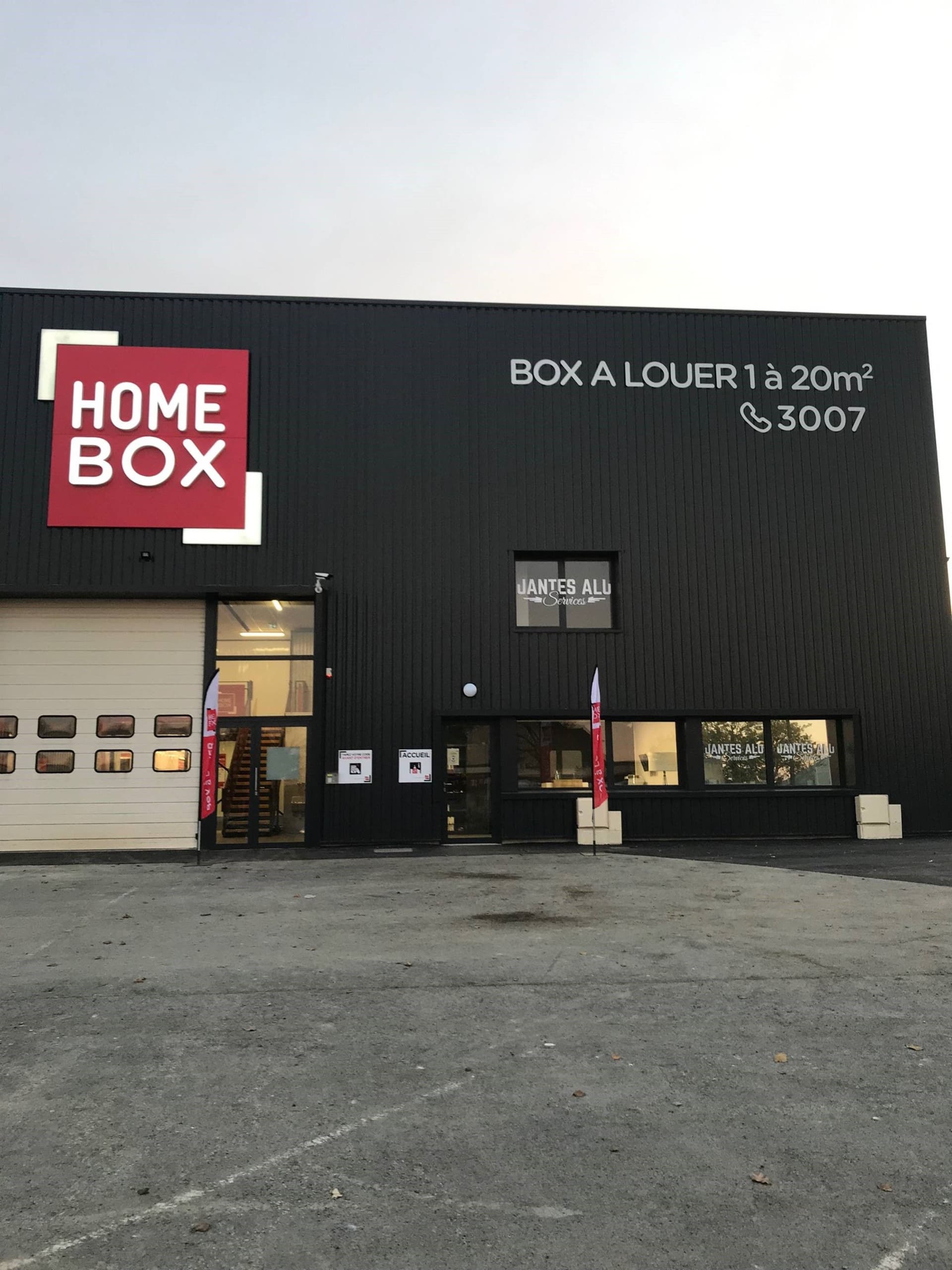 Façade noire avec enseigne rouge HOMEBOX et entrée vitrée éclairée, HOMEBOX Vitré, 92B Boulevard de Laval à Vitré