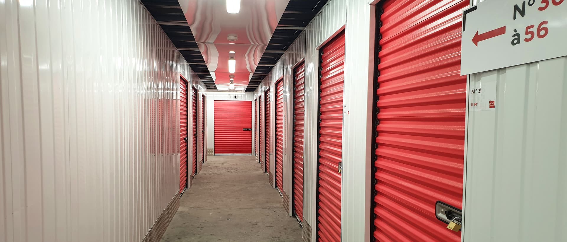 Couloir de boxes de stockage du centre HOMEBOX Ajaccio, situé à Mezzavia, avec portes roulantes rouges.