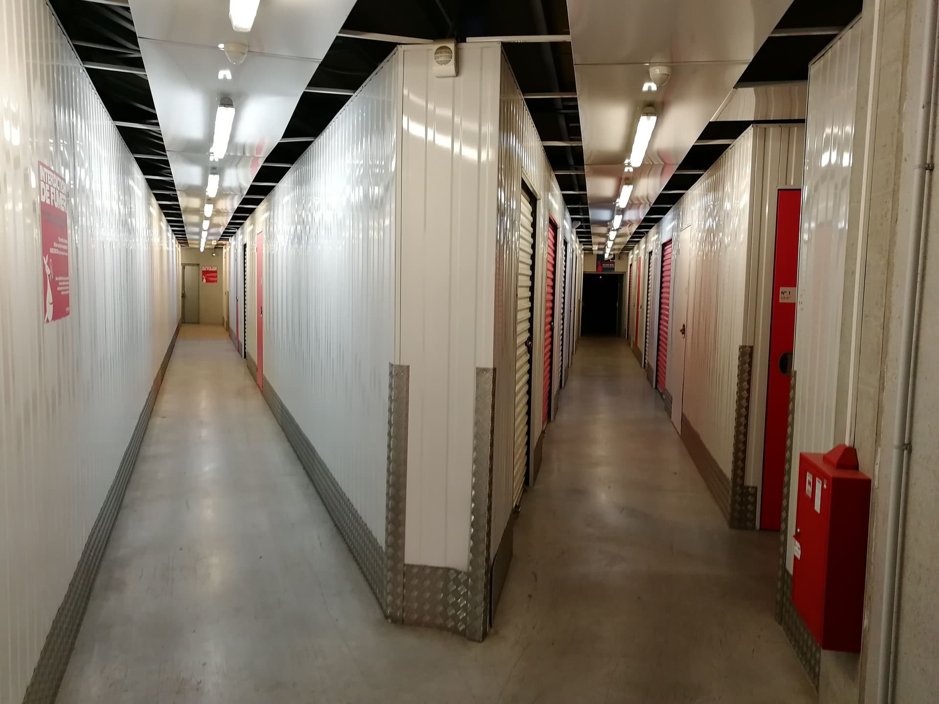 Couloir intérieur avec portes blanches et rouges de box de stockage alignés du centre HOMEBOX Tours