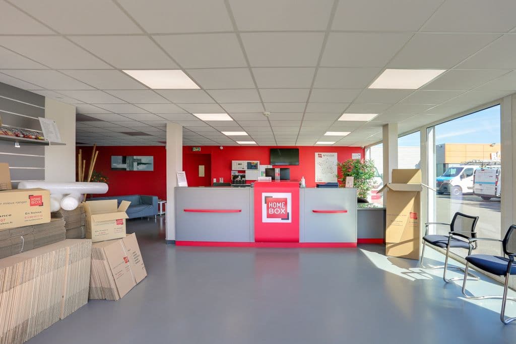 Espace accueil lumineux avec comptoir HOMEBOX, piles de cartons et baie vitrée du centre HOMEBOX Rennes Donelière