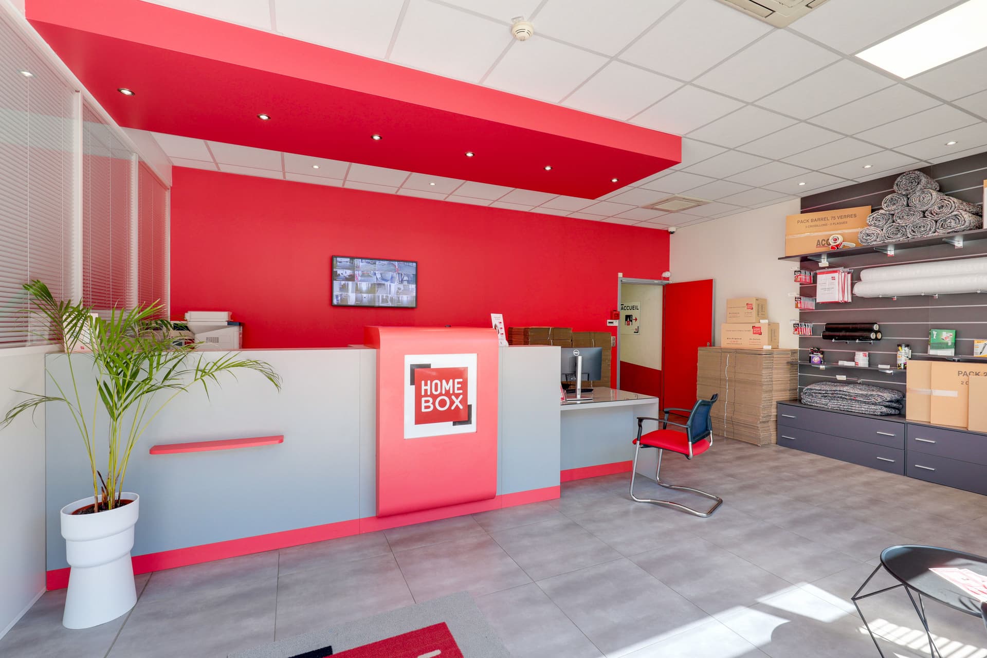 Accueil avec comptoir rouge, plante verte et espace boutique du centre HOMEBOX Quimper Gare
