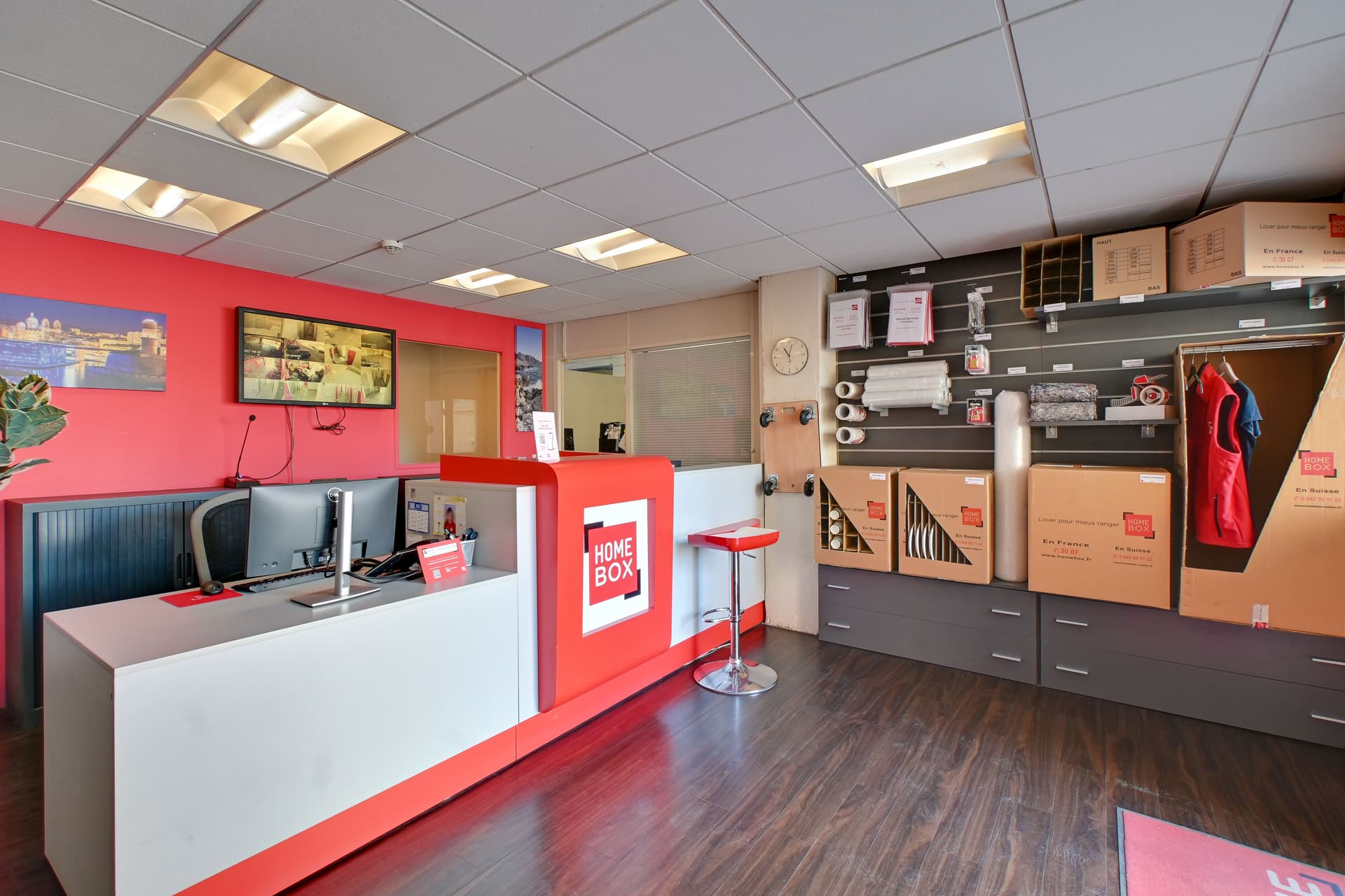 Espace d'accueil avec comptoir rouge HOMEBOX, écran d'information et boutique de cartons du centre HOMEBOX Marseille - Littoral
