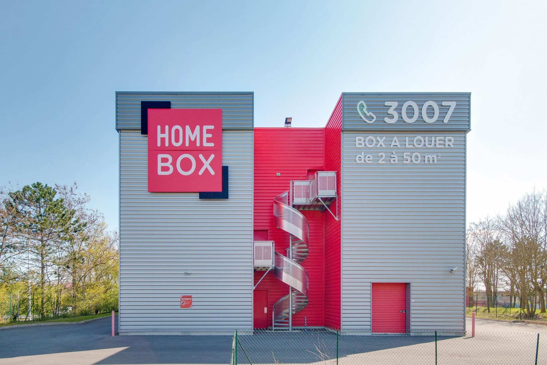Bâtiment gris avec grand logo et escalier hélicoïdal métallique en façade, HOMEBOX Reims Nord, 68 rue Charles Guggiari à Reims