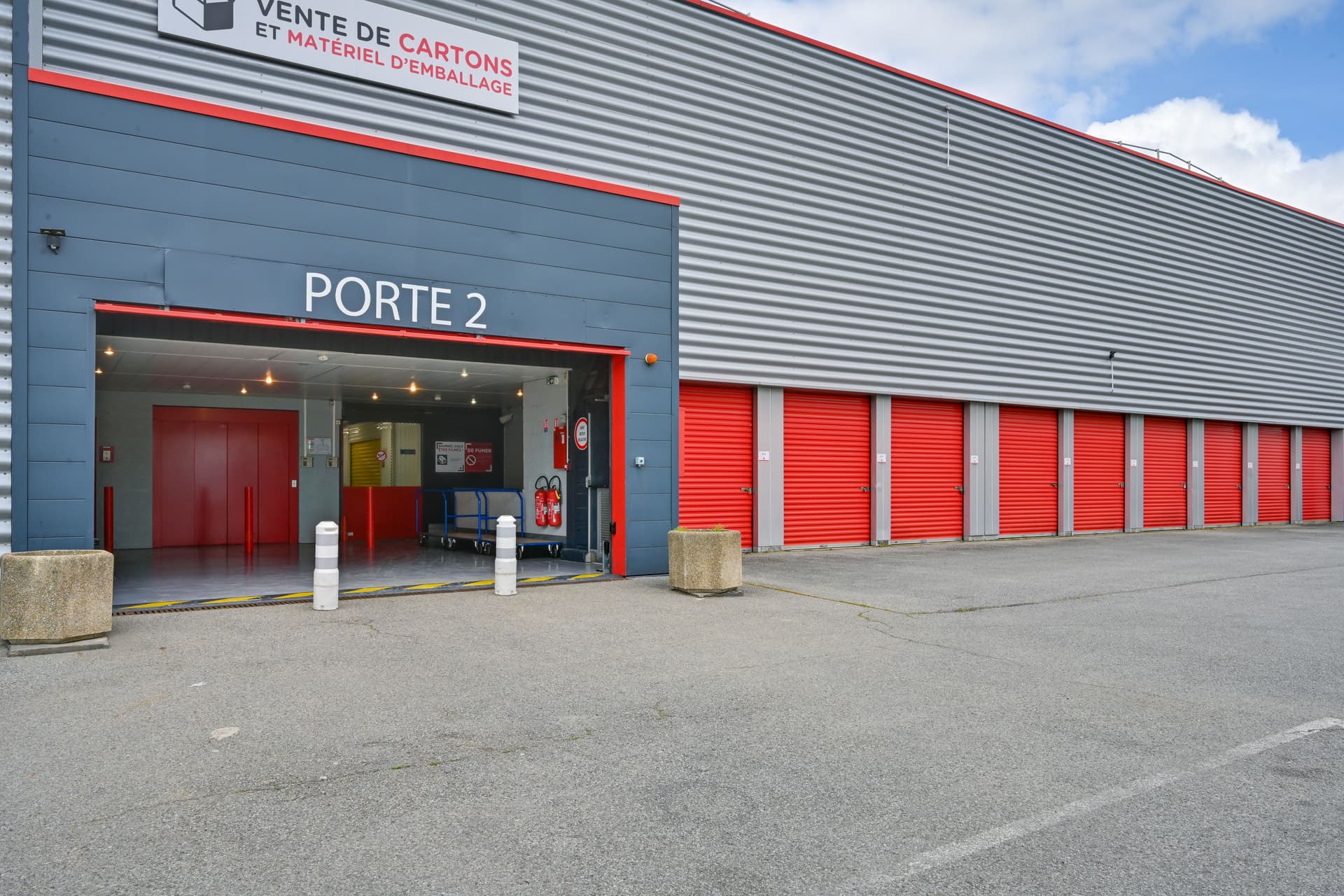 Entrée porte 2 et alignement de portes de box rouges sous enseigne vente de cartons, HOMEBOX Plaisir, 15 rue Descartes à Plaisir