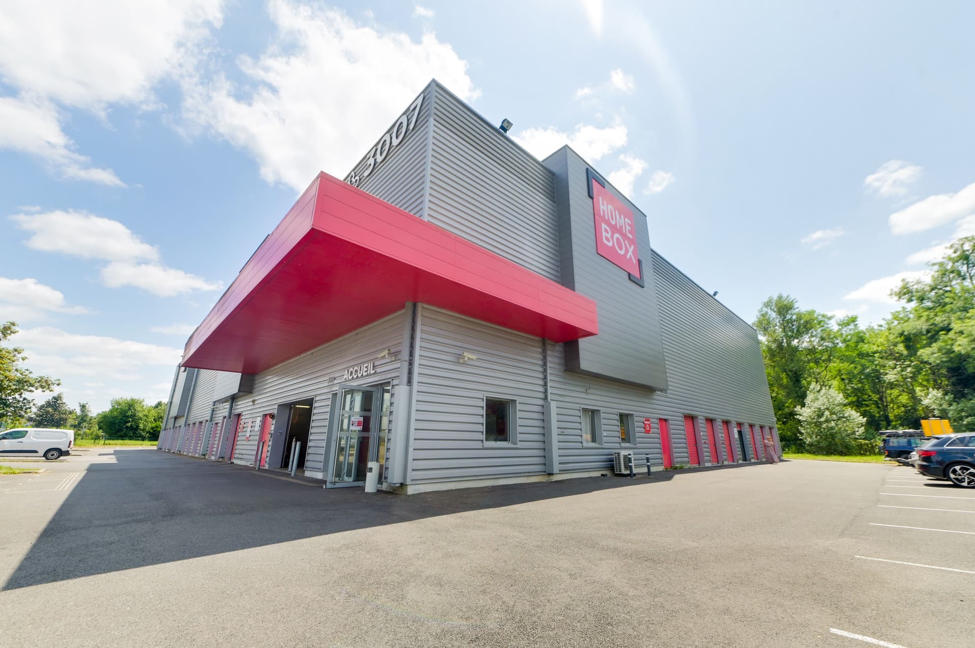 Vue d'angle du bâtiment gris et rouge avec auvent d'accueil, HOMEBOX Pau, Chemin de la Saligue à Lons