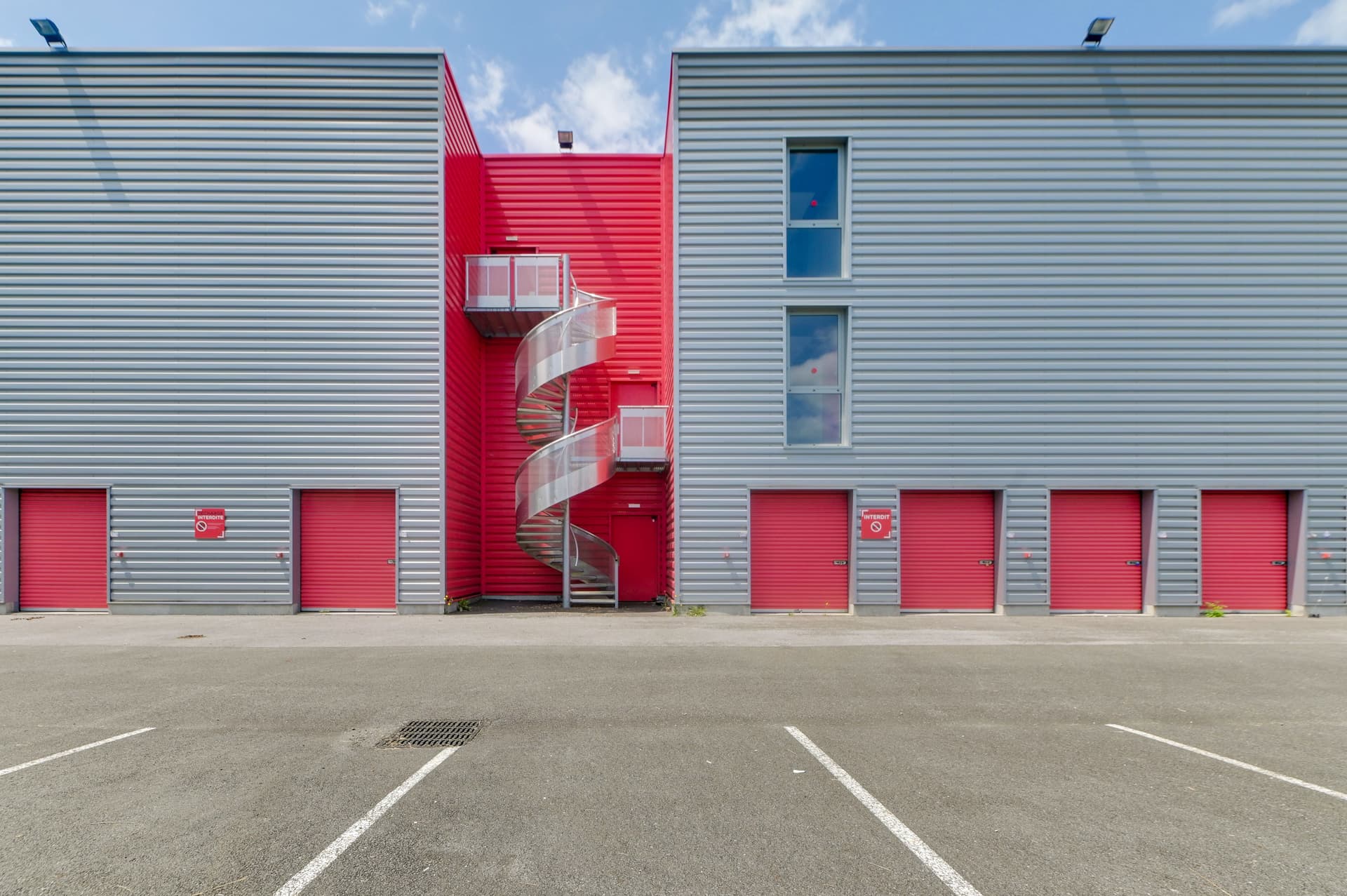 Façade arrière avec escalier hélicoïdal rouge et portes de boxes, HOMEBOX Pau, Chemin de la Saligue à Lons
