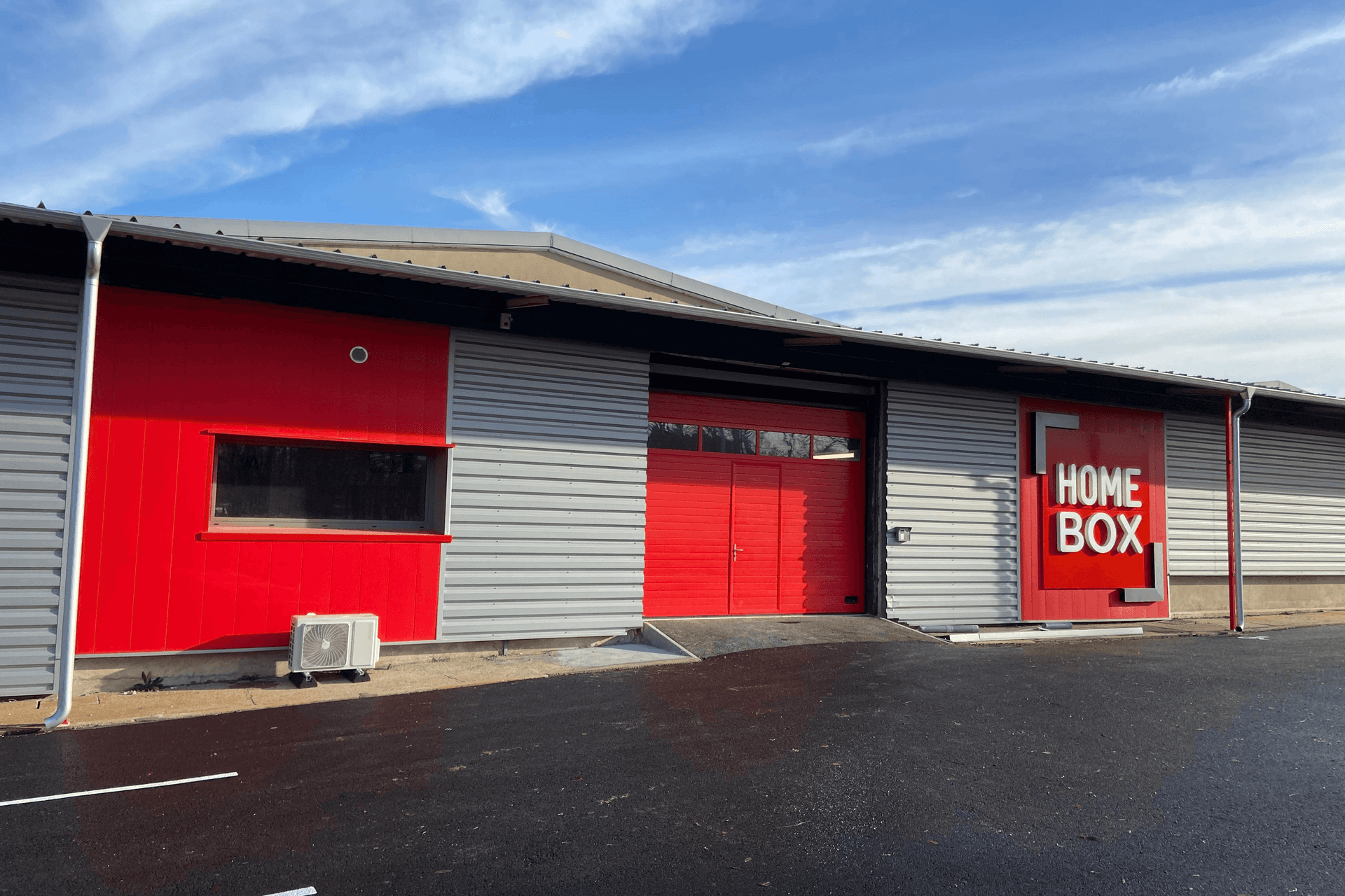 Vue extérieure du centre HOMEBOX Bourges, Allée Napoléon III, avec entrée principale et logo rouge.