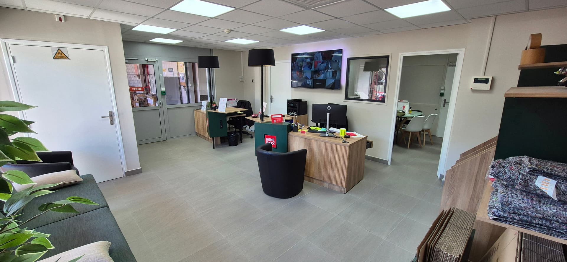 Bureau d'accueil moderne avec écrans de vidéosurveillance et coin lecture du centre HOMEBOX Nanterre La Défense