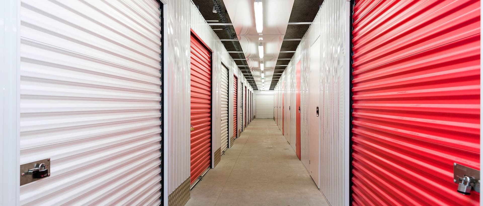 Couloir intérieur avec portes roulantes rouges et blanches au centre HOMEBOX Caen Ouest.