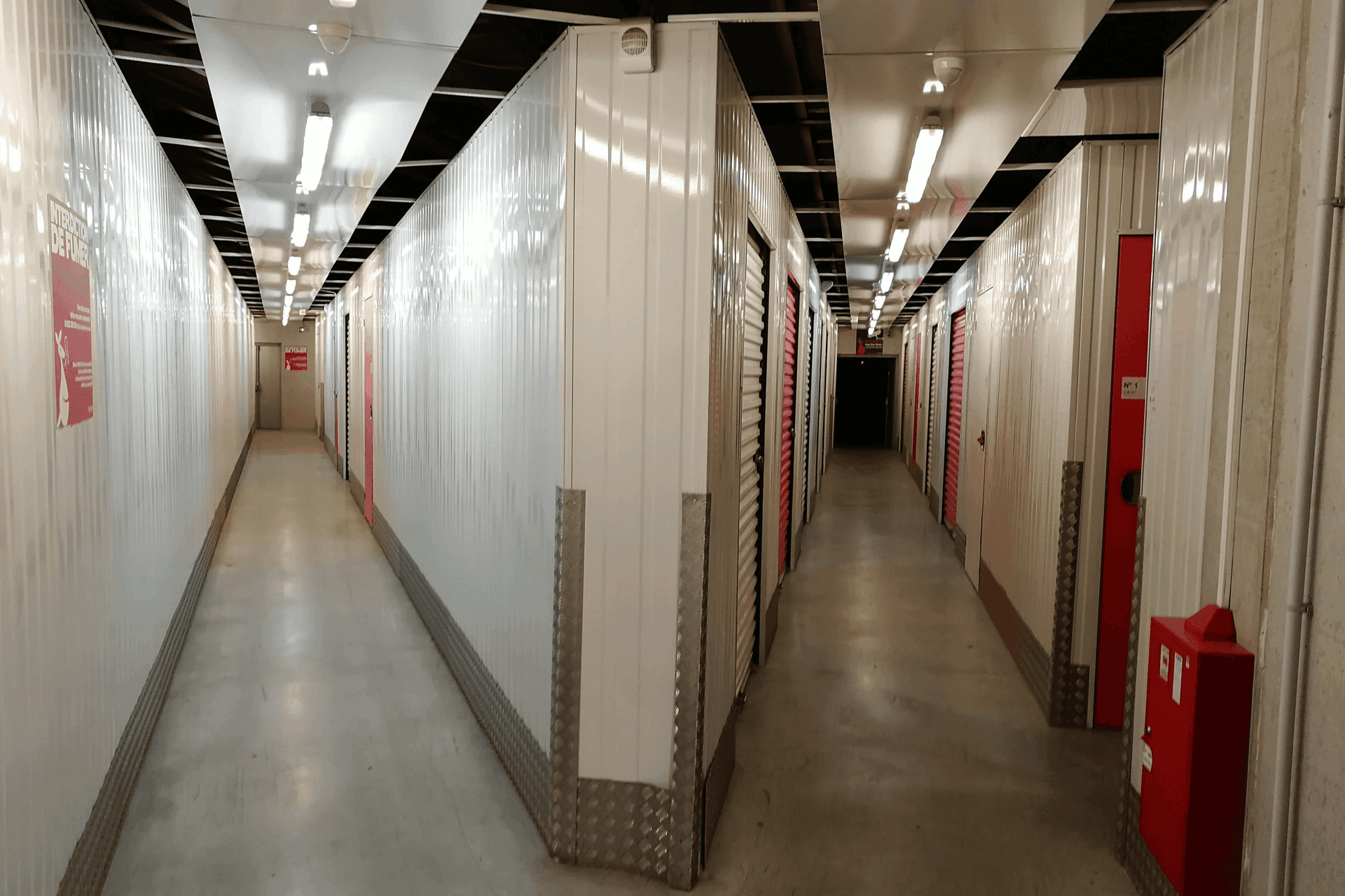 Couloir intérieur avec portes roulantes blanches et rouges au centre HOMEBOX Clermont-Ferrand.