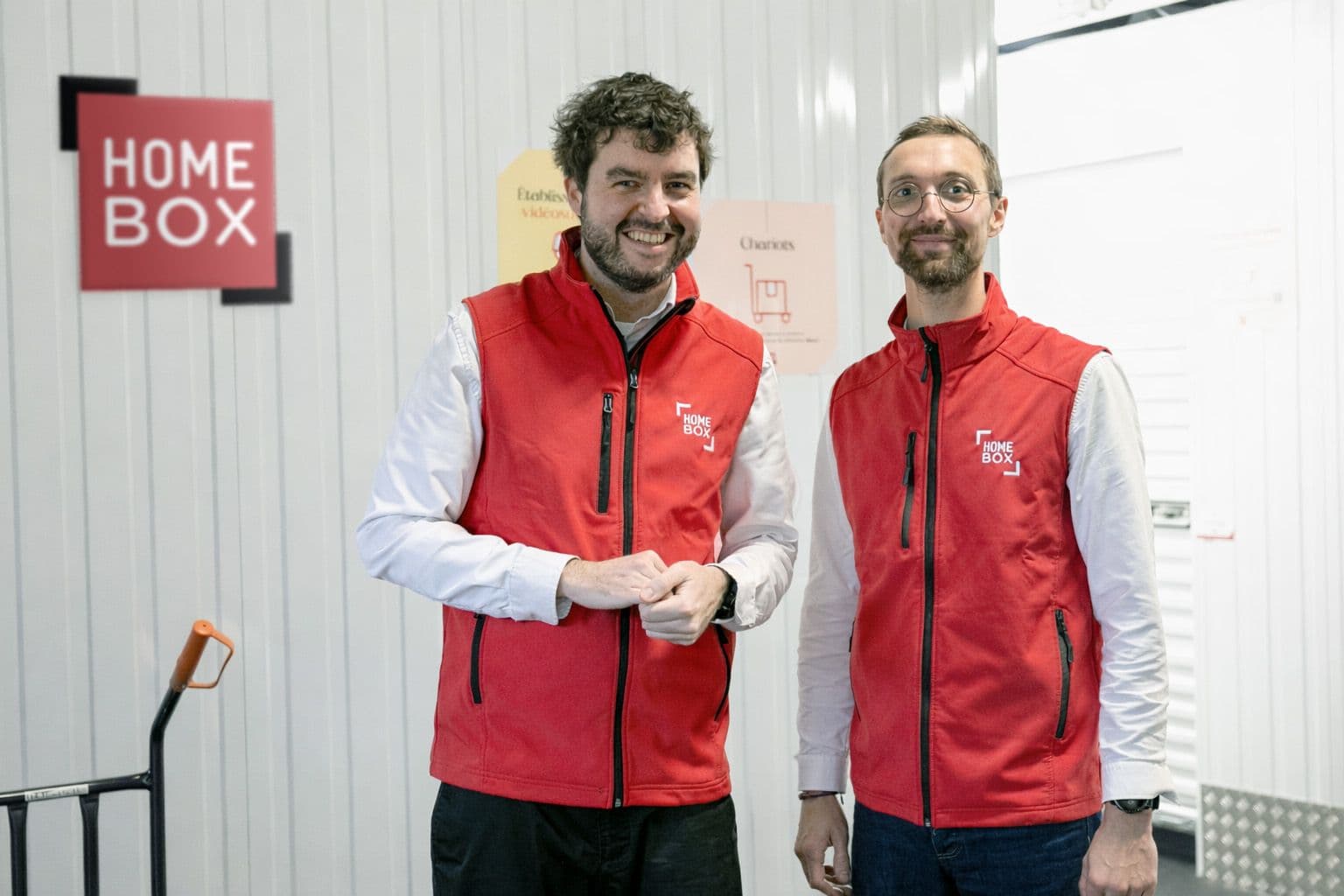 Équipe souriante en gilet rouge devant le logo HOMEBOX à l'accueil du centre HOMEBOX Dunkerque